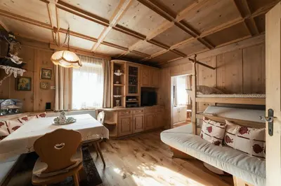 a bedroom with a bunk bed and a table and a couch at Ciasa Ilda - Charming house 120 m2 in La Valle