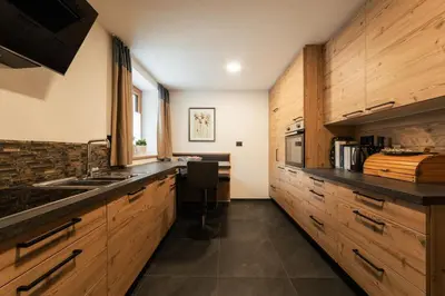 a kitchen with wooden cabinets and a sink at Ciasa Ilda - Charming house 120 m2 in La Valle
