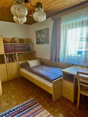 a bedroom with a bed and a desk and a window at Ciasa Ilda - Charming house 120 m2 in La Valle
