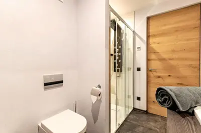a bathroom with a toilet and a glass door at Villa Lara Laerche in Castelrotto