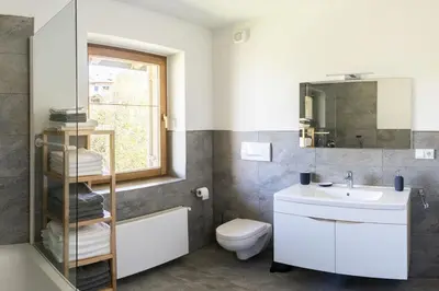 a bathroom with a sink and a toilet and a mirror at Large apartment with panoramic view in Meluno