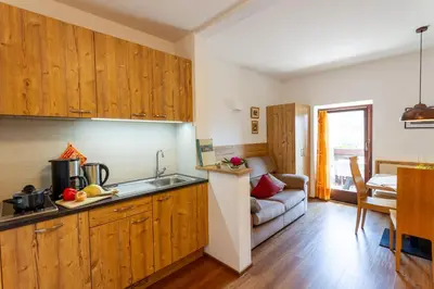 a kitchen with wooden cabinets and a living room at Appartments Moarhof in Vols am Schlern