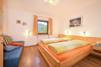 a bedroom with a large bed and a chair at Putzerhof - Urlaub auf dem Bauernhof in Brixen
