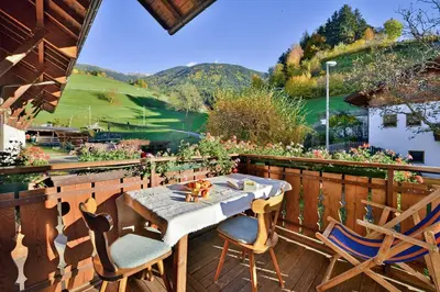 a patio with a table and chairs on a deck at Putzerhof - Urlaub auf dem Bauernhof in Brixen
