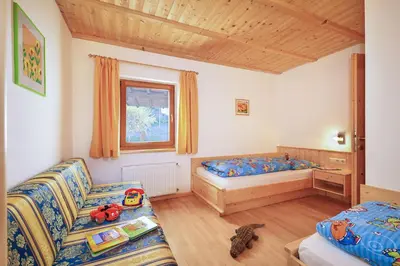 a room with a couch and a bed and a window at Putzerhof - Urlaub auf dem Bauernhof in Brixen