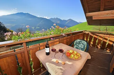 a table with two glasses of wine and fruit on a balcony at Putzerhof - Urlaub auf dem Bauernhof in Brixen