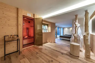a room with wooden flooring and a hallway with a room with a couch at Putzerhof - Urlaub auf dem Bauernhof in Brixen