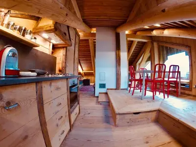 a kitchen with wooden cabinets and red chairs in a cabin at Stunning Luxury House in Cortina dʼAmpezzo