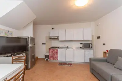 a living room with a couch and a kitchen at Tabia delle Rose in Piaia