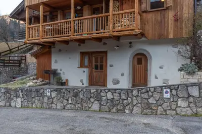a house with a balcony on top of a stone wall at Tabia delle Rose in Piaia