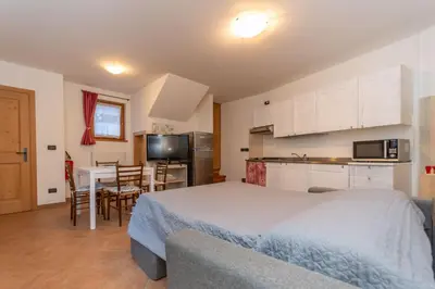 a bedroom with a bed and a kitchen with a table at Tabia delle Rose in Piaia
