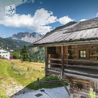 a wooden cabin with a mountain in the background at Appartamenti Pra Fiorì in Vigo di Fassa