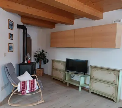 a living room with a tv and a chair at Appartamenti Pra Fiorì in Vigo di Fassa