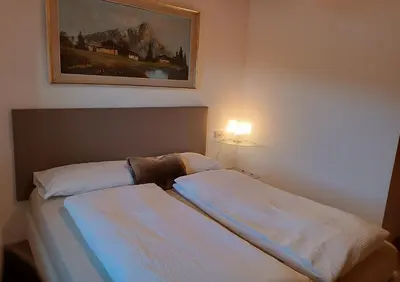 a bedroom with two beds and a painting on the wall at Appartamenti Pra Fiorì in Vigo di Fassa