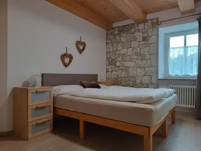 a bedroom with a bed and a stone wall at Appartamenti Pra Fiorì in Vigo di Fassa