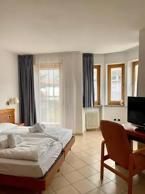 a bedroom with a bed and a desk and a television at Goldenhof in Ora/Auer