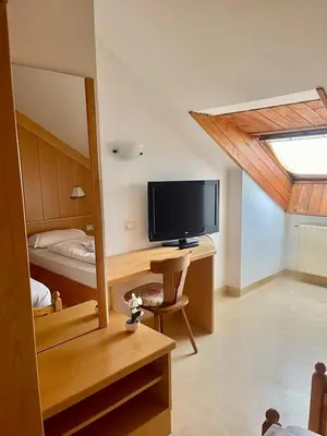 a bedroom with a desk with a television and a bed at Goldenhof in Ora/Auer