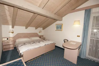 a bedroom with a bed and a desk in it at Hotel Villa Mozart in Pozza di Fassa