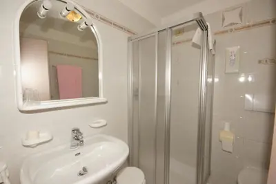 a white bathroom with a shower and a sink at Hotel Villa Mozart in Pozza di Fassa