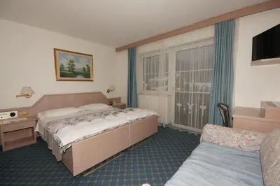 a hotel room with a bed and a couch at Hotel Villa Mozart in Pozza di Fassa