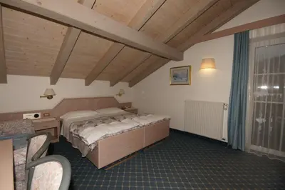 a bedroom with a bed and a table and chairs at Hotel Villa Mozart in Pozza di Fassa