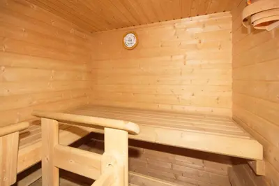 a wooden sauna with a bench and a clock at Hotel Villa Mozart in Pozza di Fassa