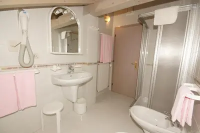 a white bathroom with a sink and a shower at Hotel Villa Mozart in Pozza di Fassa