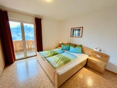 a bedroom with a bed and a large window at Haslingerhof - Ferienwohnung Ortler in Saltusio