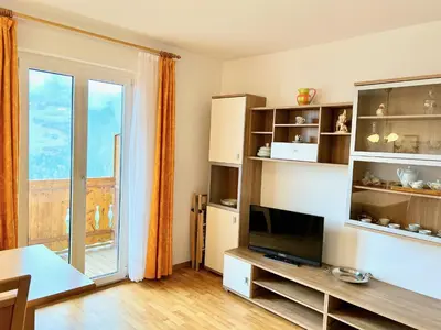 a living room with a tv and a large window at Haslingerhof - Ferienwohnung Ortler in Saltusio
