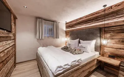 a bedroom with a white bed with a wooden wall at La Mendola Alm-Chalet in Mendola