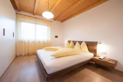 a bedroom with a large white bed and a window at Appartements St Urban in Cornaiano