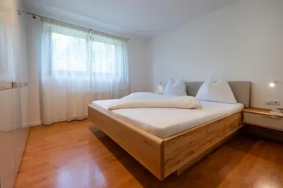 a bedroom with a bed with white sheets and a window at Appartements St Urban in Cornaiano