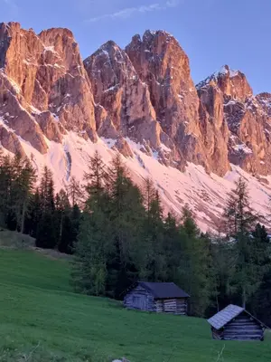 two barns in a field in front of a mountain at Dolomiten Home in Villnoss