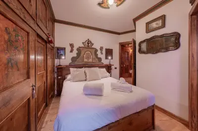 a bedroom with a large bed with a wooden headboard at Cortina City Center Alpine Apartment with Private Garage in Cortina dʼAmpezzo