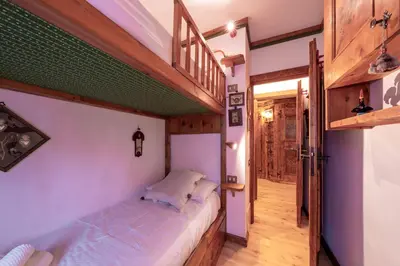 a small bedroom with a bed and a staircase at Cortina City Center Alpine Apartment with Private Garage in Cortina dʼAmpezzo