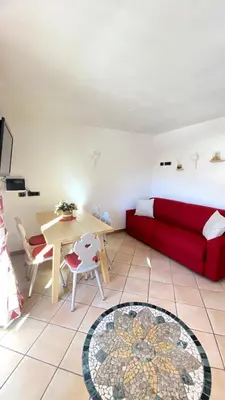a living room with a red couch and a table at Ciasa Coderoppola in Moena