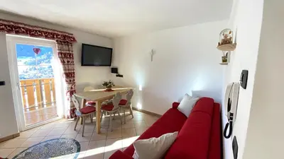a living room with a red couch and a table at Ciasa Coderoppola in Moena