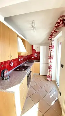 a kitchen with red tile flooring and a white refrigerator at Ciasa Coderoppola in Moena