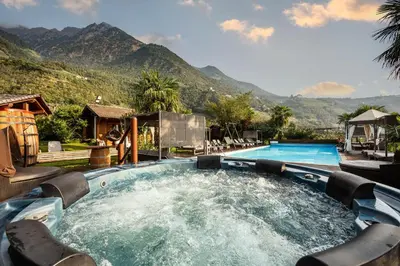 a pool with a hot tub with mountains in the background at Ruster Resort in Lagundo