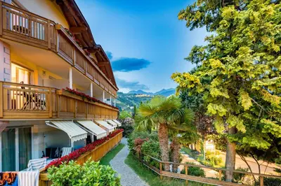 a building with balconies and trees and a pathway at Ruster Resort in Lagundo