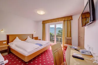 a hotel room with a bed and a desk and a television at Ruster Resort in Lagundo
