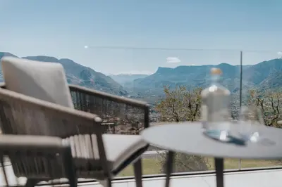 a table and chairs on a balcony with a view of mountains at La Vista Panoramic Hideaway - Adults only in Tirolo