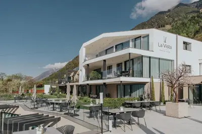 a hotel with tables and chairs in front of a building at La Vista Panoramic Hideaway - Adults only in Tirolo