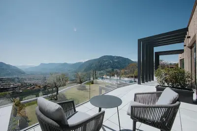 a balcony with chairs and a table and a view at La Vista Panoramic Hideaway - Adults only in Tirolo
