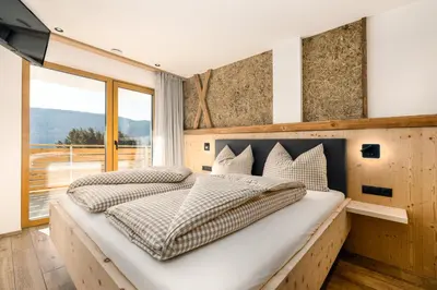 a bedroom with two beds and a large window at Forchnerhof Nature & Mountain View Apartments in Terento