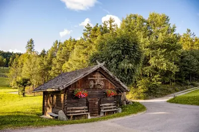 a small wooden cabin with flowers on the side of a road at Forchnerhof Nature & Mountain View Apartments in Terento