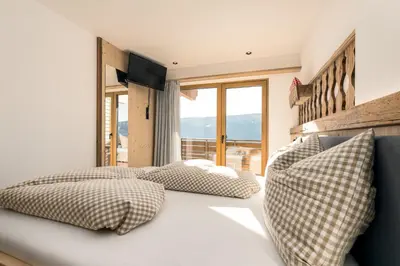 a bedroom with two beds and a large window at Forchnerhof Nature & Mountain View Apartments in Terento