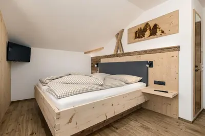 a bed in a room with a wooden headboard at Forchnerhof Nature & Mountain View Apartments in Terento