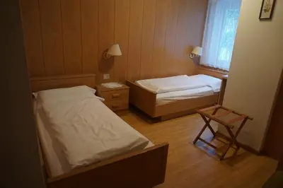 a small room with two beds and a chair at Hotel & Residence Sylvanerhof in Chiusa