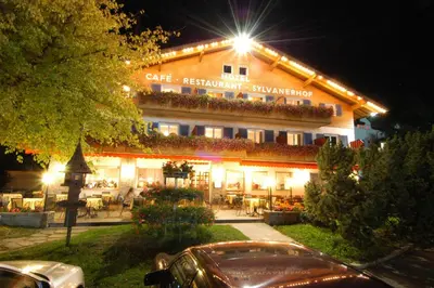 a building with a restaurant with tables and chairs at night at Hotel & Residence Sylvanerhof in Chiusa